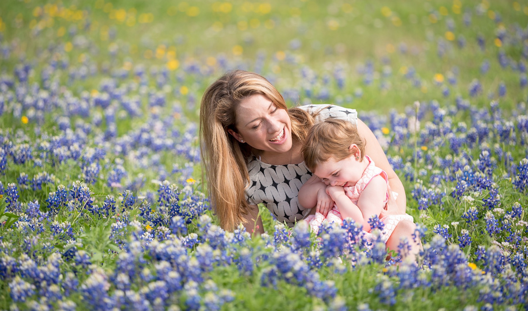 a mother and a baby sitting in a field of flowers